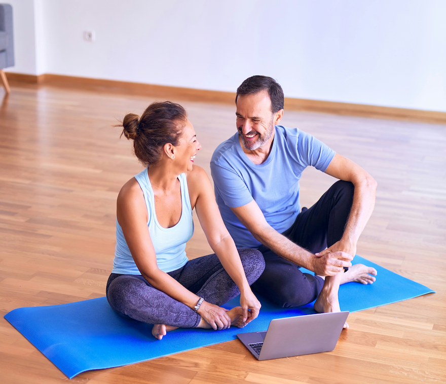 A couple sitting on a yoga mat getting ready for some movement and exercise