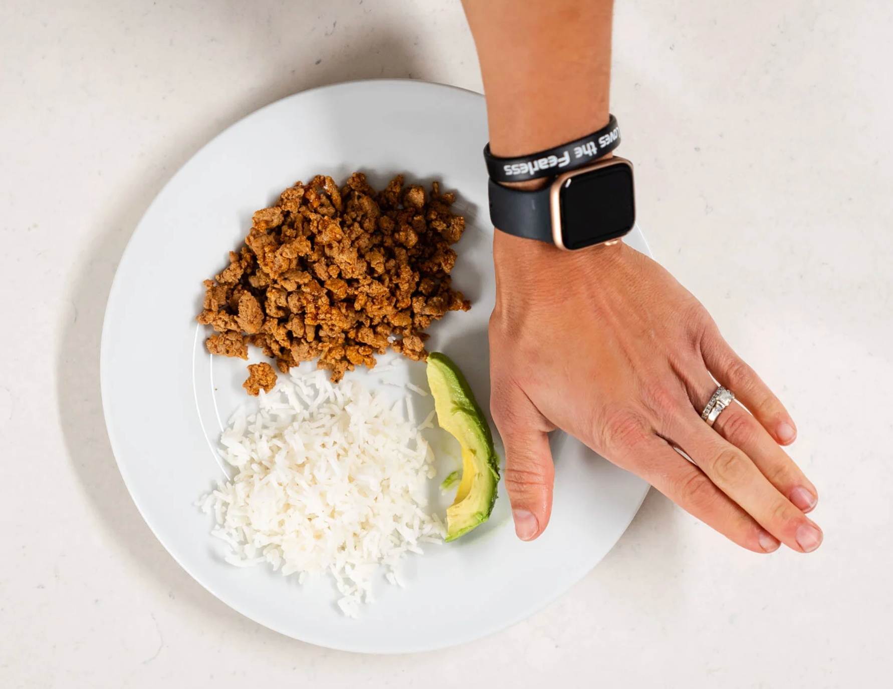A plate of healthy food with a hand held over it.