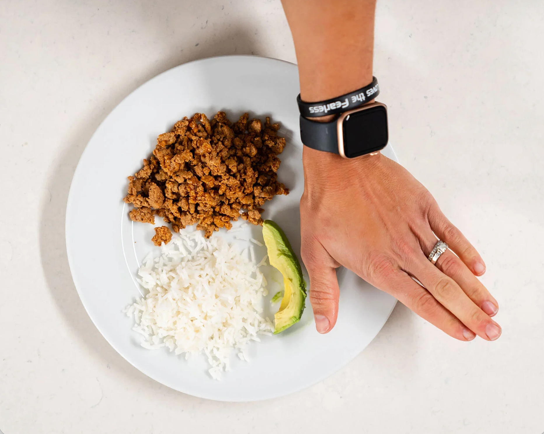 Someone holding their hand over a plate of food to show the palm method diet or fist diet rule.