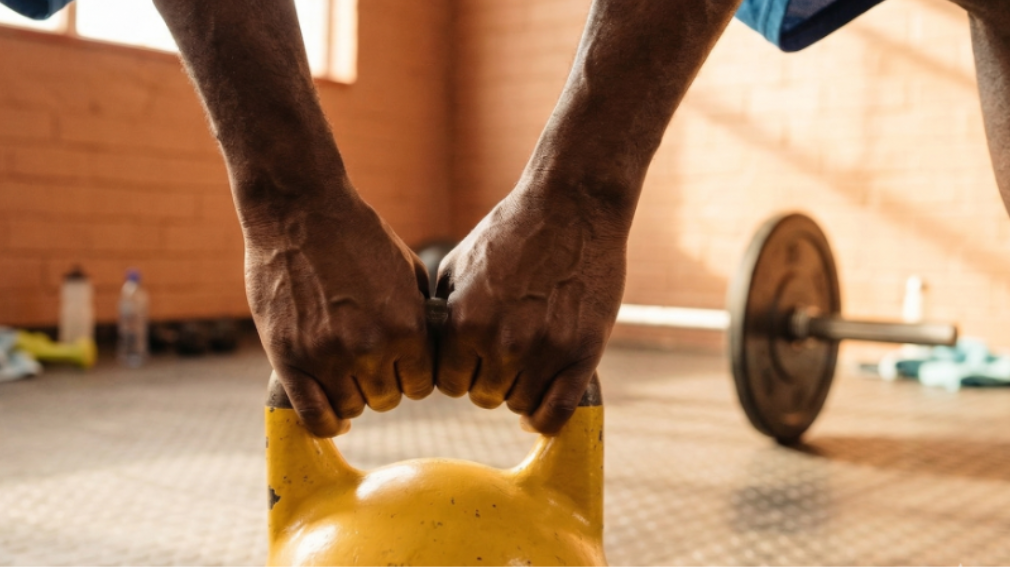 A person gripping a kettlebell with two hands in the gym.