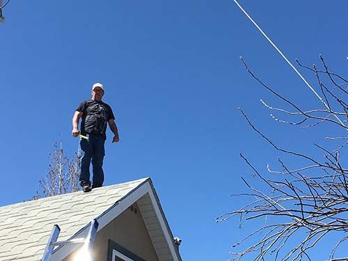 A man is standing on the roof of a house.