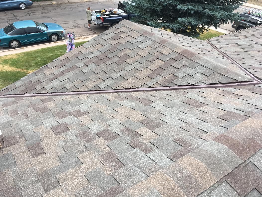 An aerial view of a roof with a blue car parked in the background.