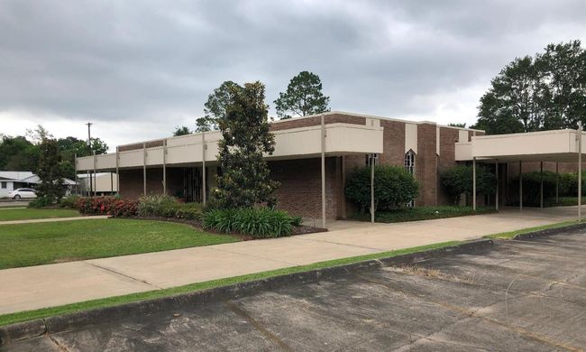 The front door of a house with a porch and plants in front of it.