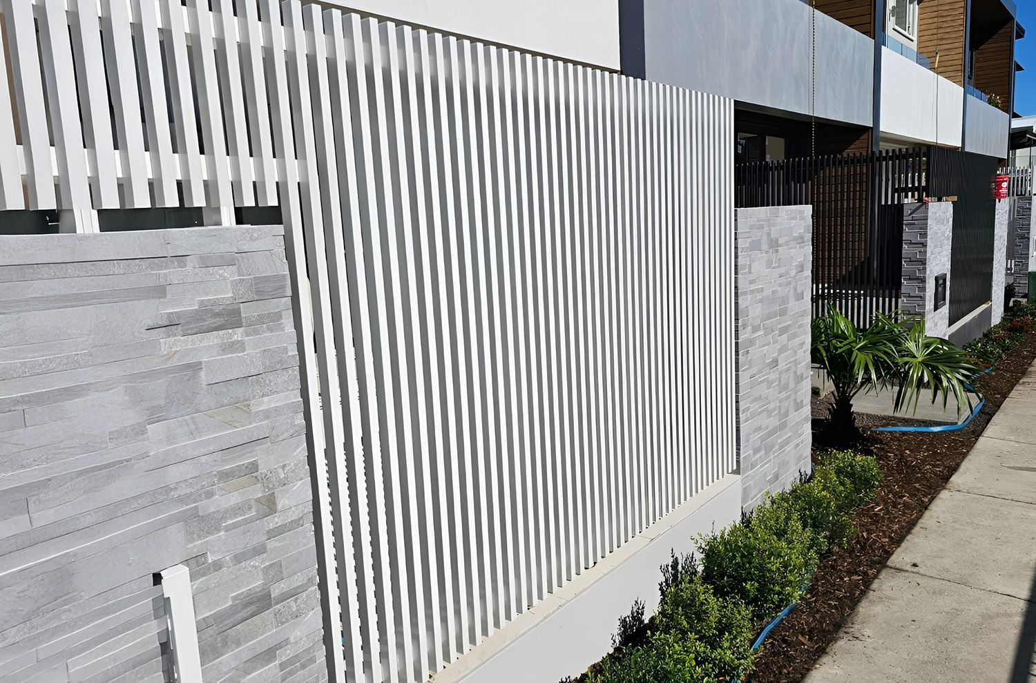 White Slatted Fence with Stone Accents