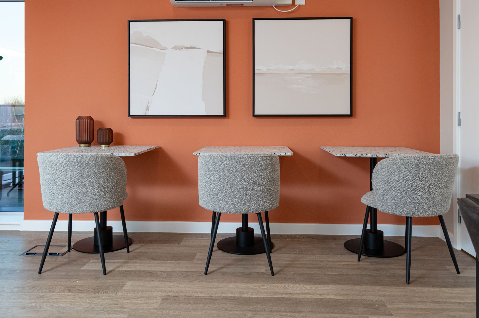 A room with three tables and chairs and two paintings on the wall at Walton Court.