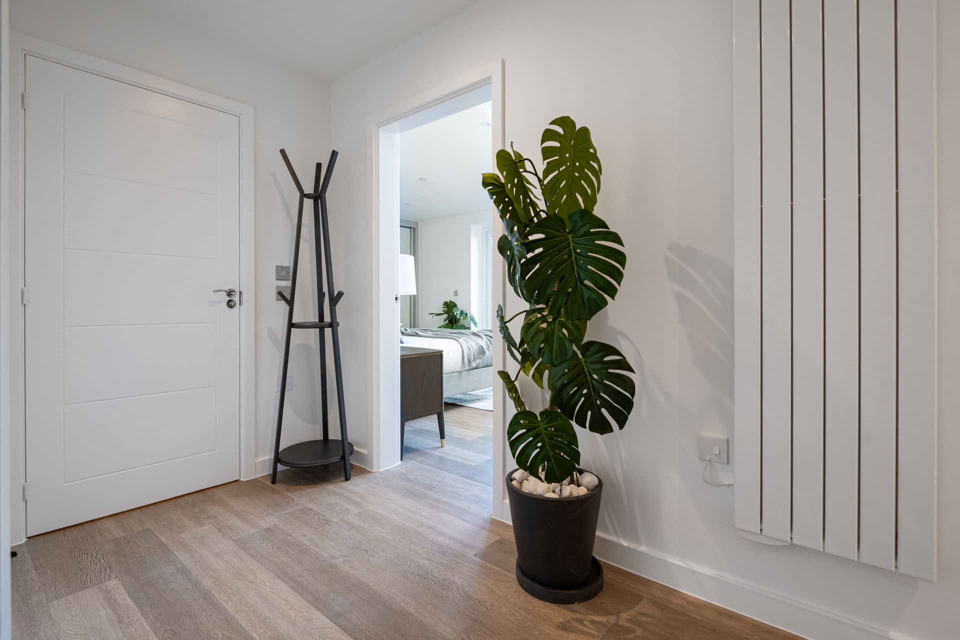 A potted plant is sitting in a hallway next to a coat rack at Walton Court.