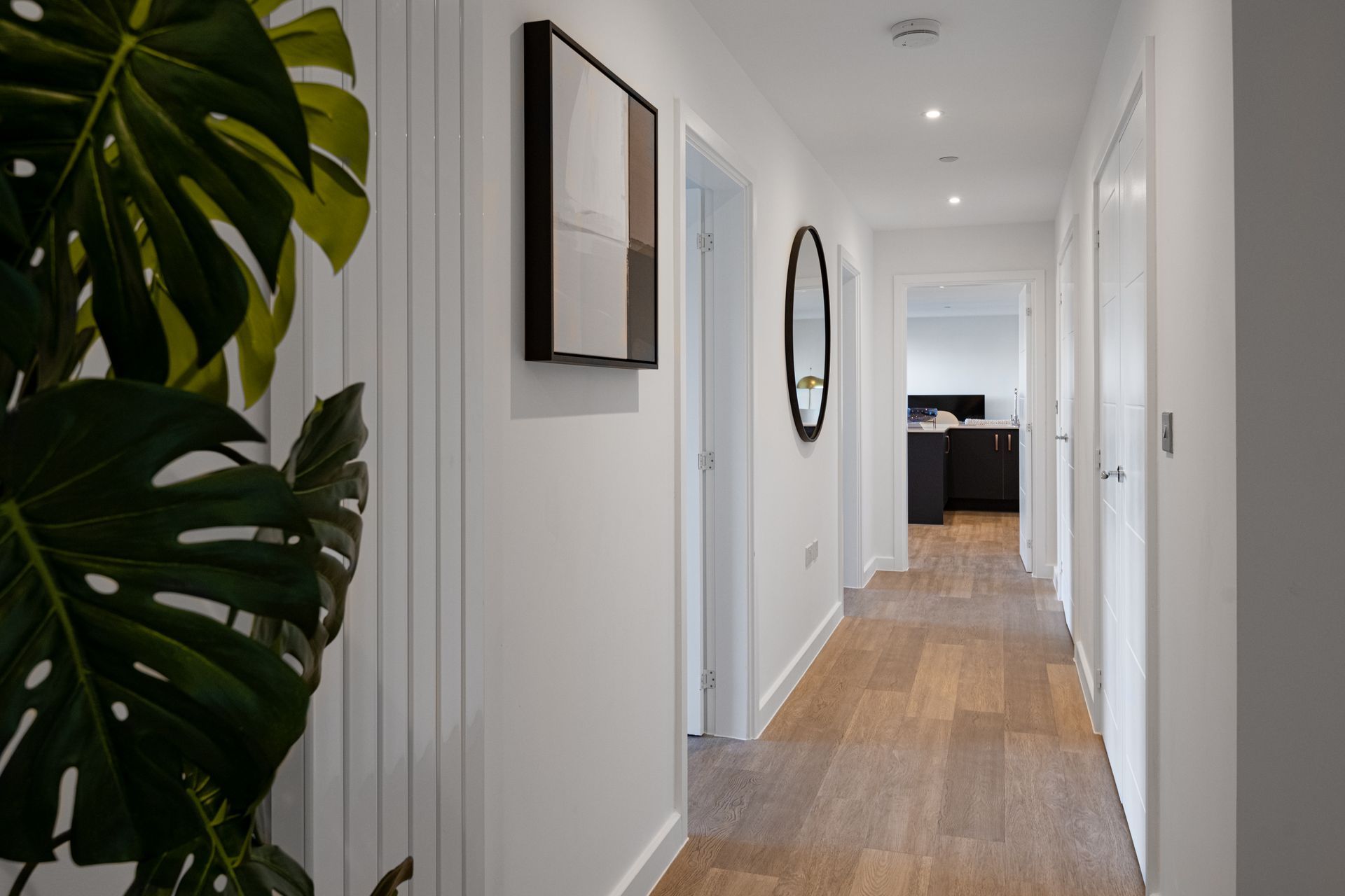 A long hallway with a plant in the foreground and a picture on the wall at Walton Court.