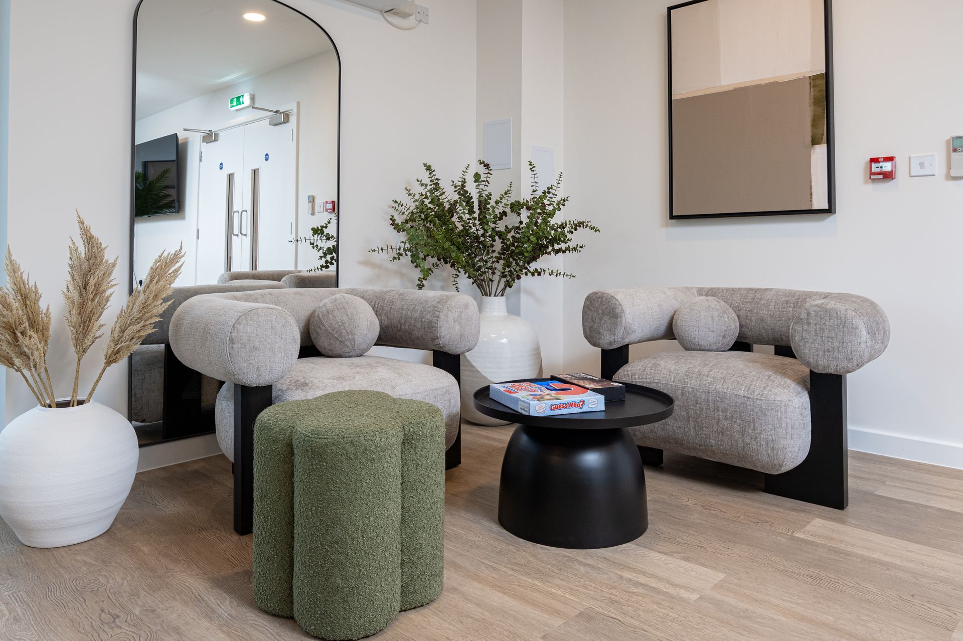 A living room with two chairs , a table , and a mirror at Walton Court.