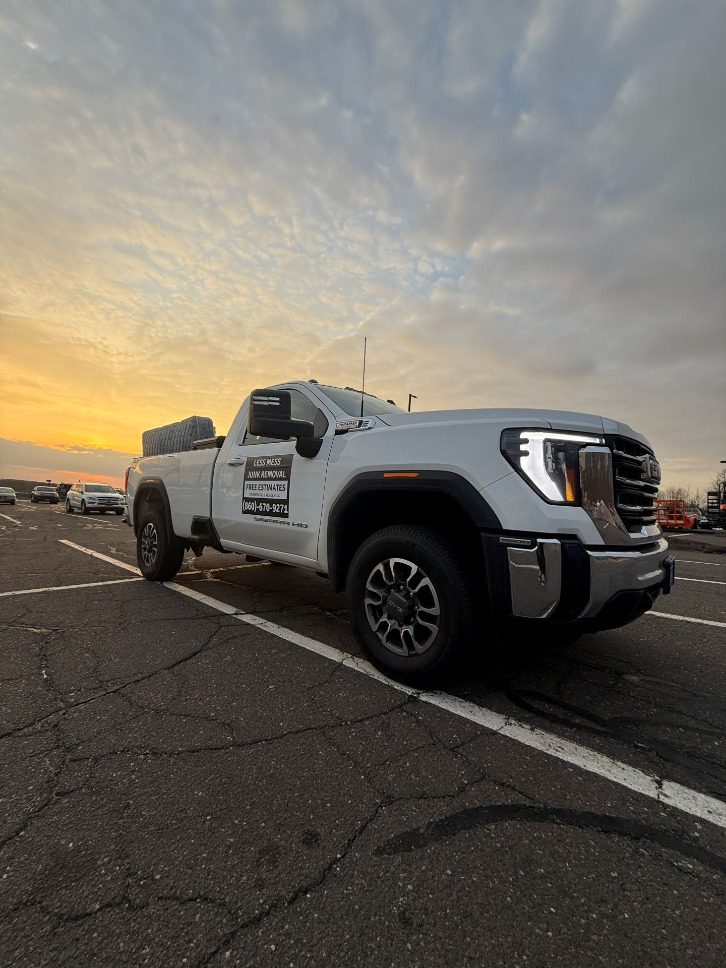 White pickup truck parked on asphalt with sunset background.