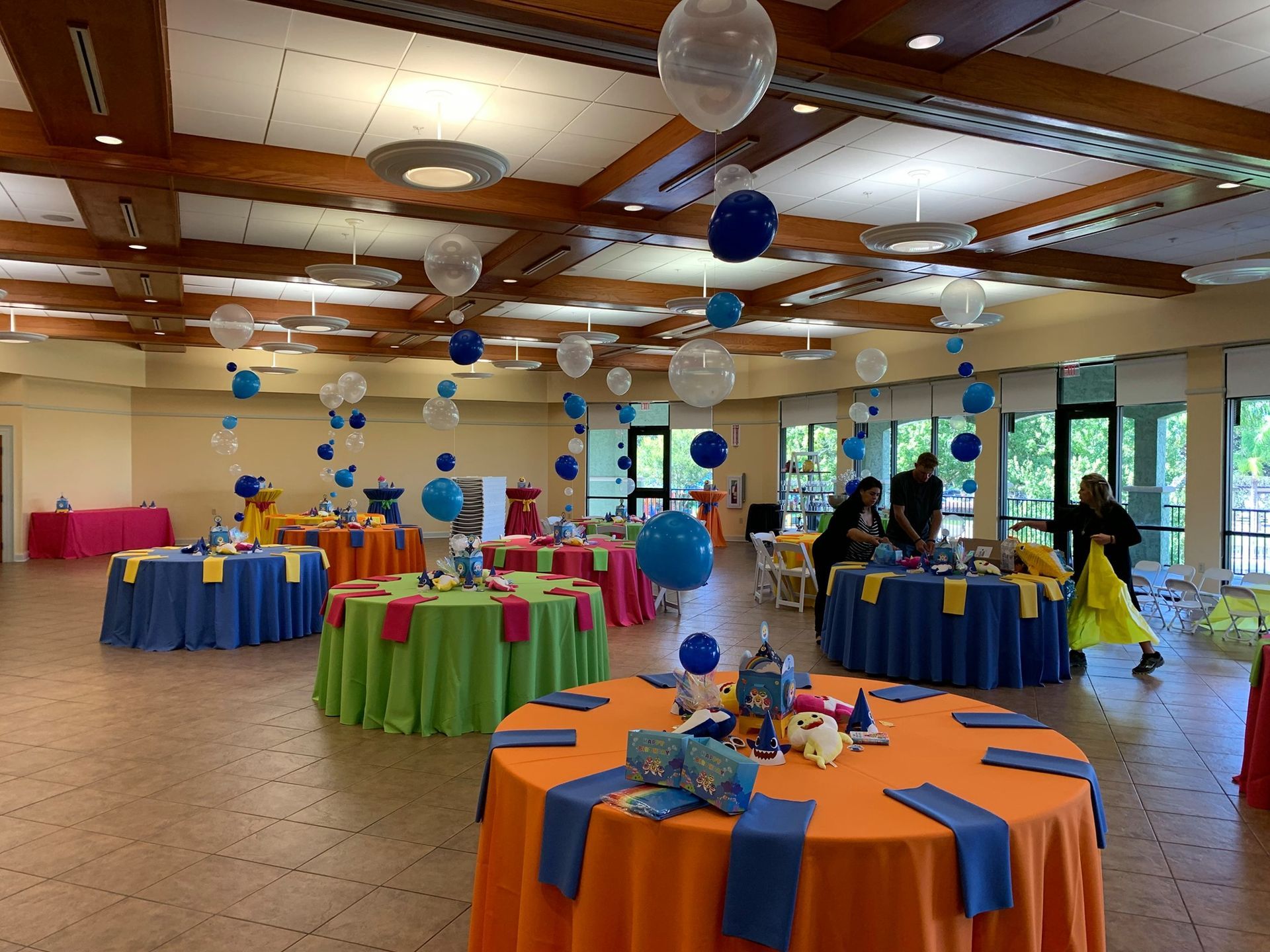 A large room with tables and balloons hanging from the ceiling