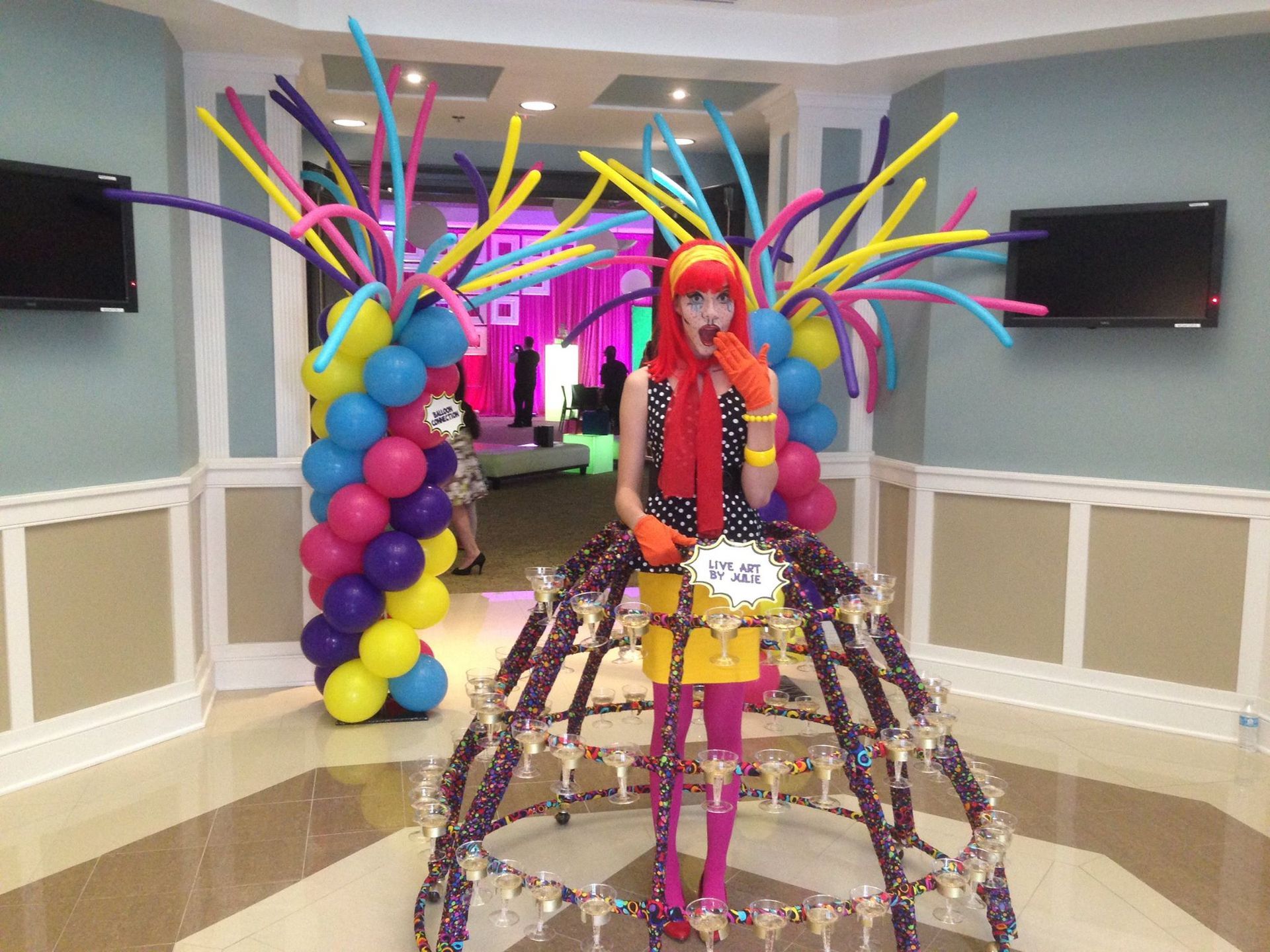 A woman in a clown costume is standing in front of balloons