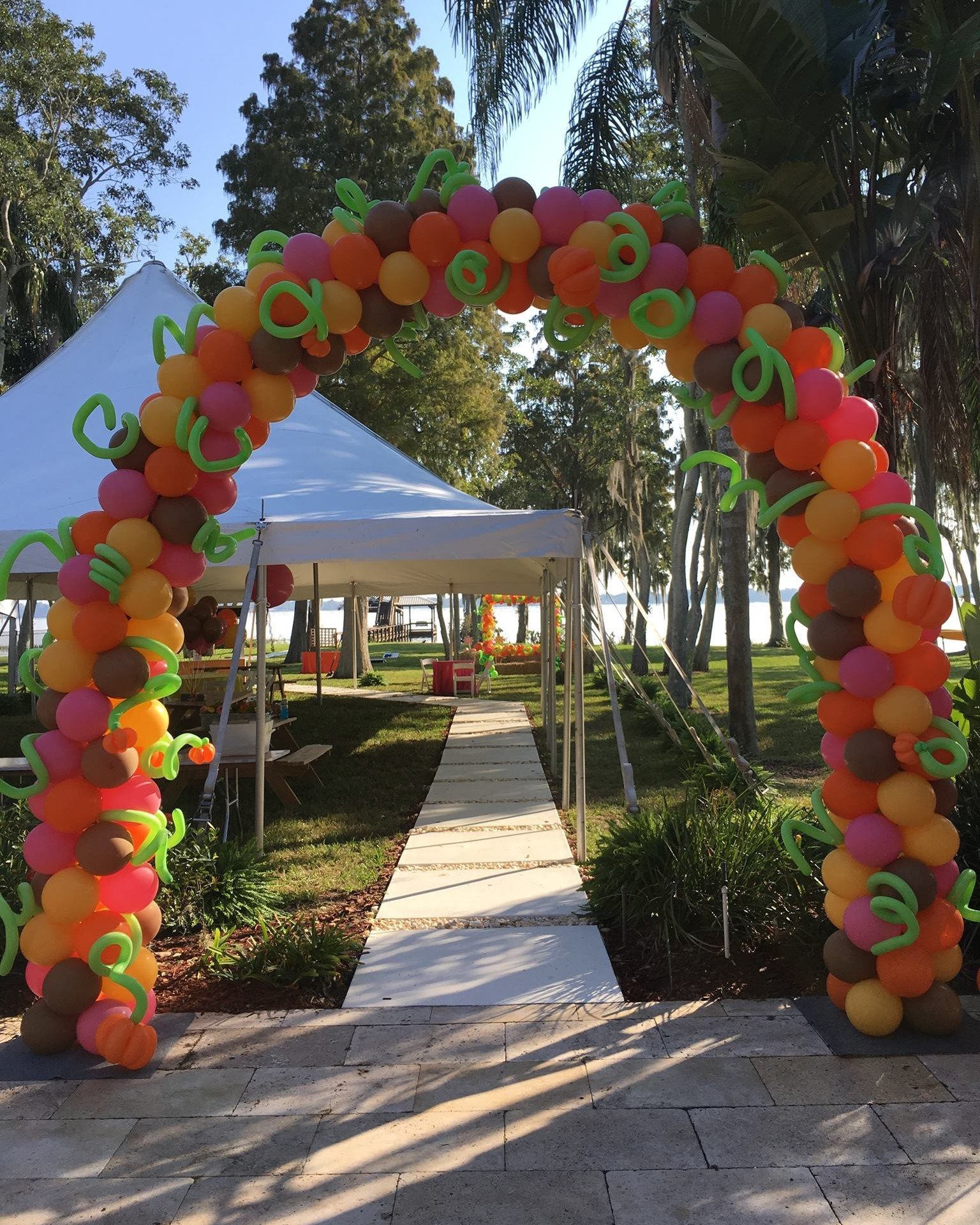 A large arch made of balloons leading to a tent