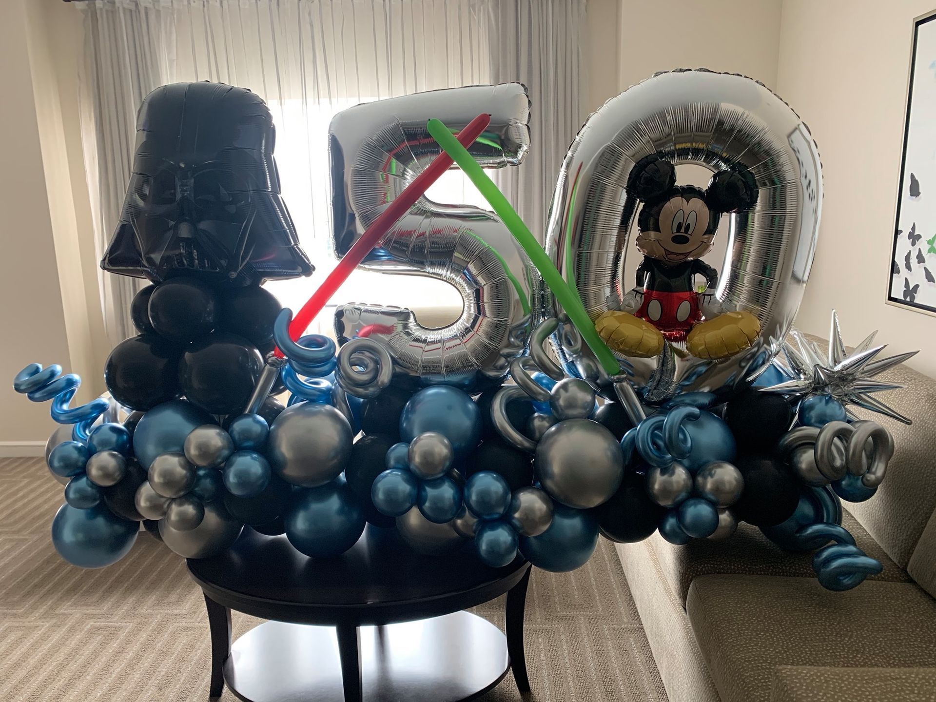 A table topped with balloons and a darth vader and mickey mouse balloon.