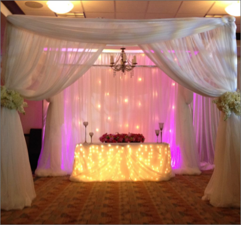 A table with flowers and lights on it under a canopy