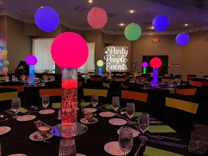 A room filled with tables and chairs and glow in the dark balloons.