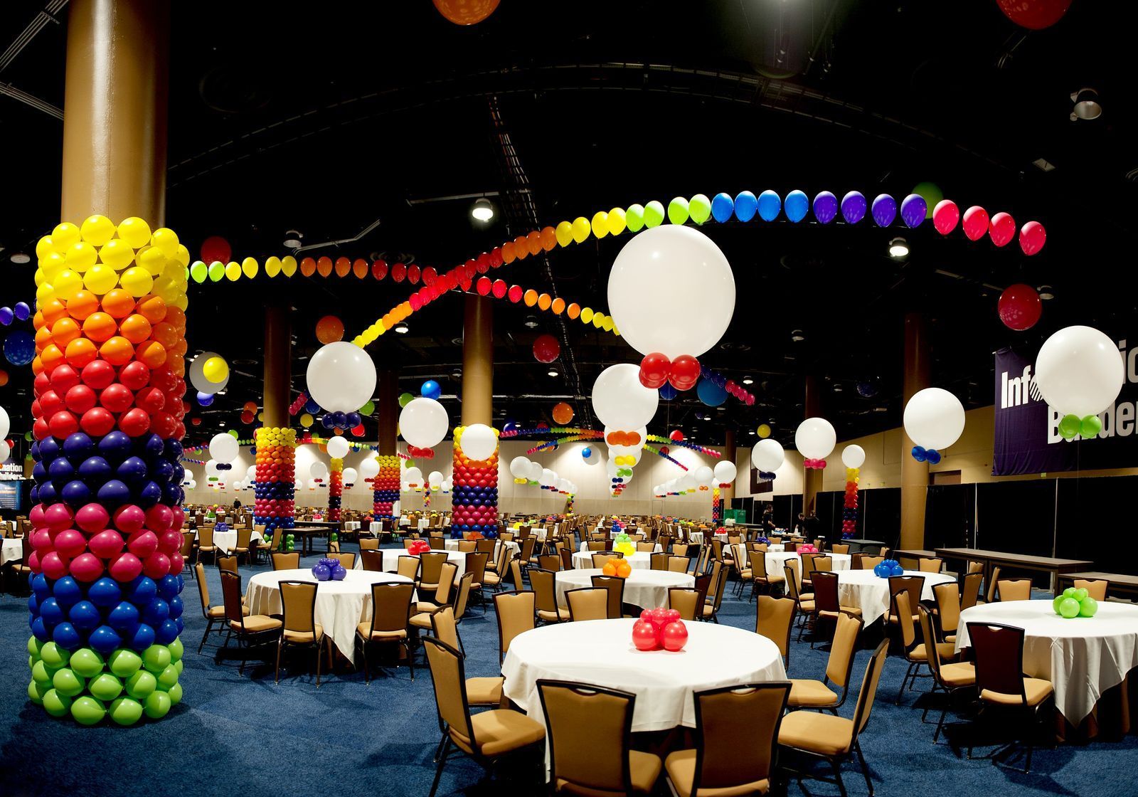 A large room with tables and chairs decorated with balloons