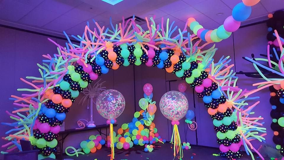 A room decorated with neon balloons and glow in the dark tape.