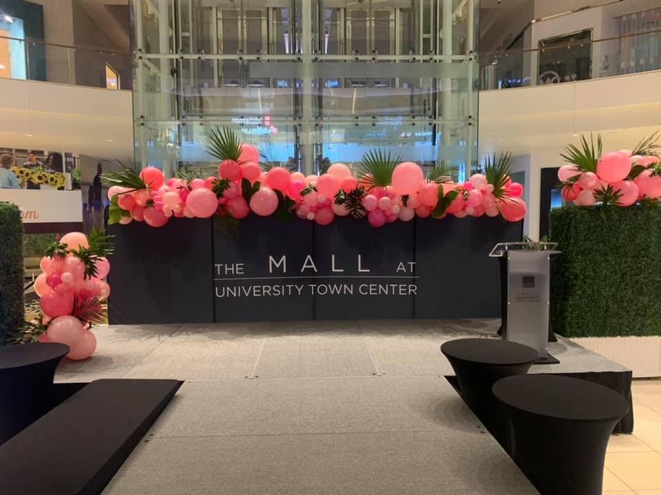 The mall at university town center is decorated with pink balloons and flowers.