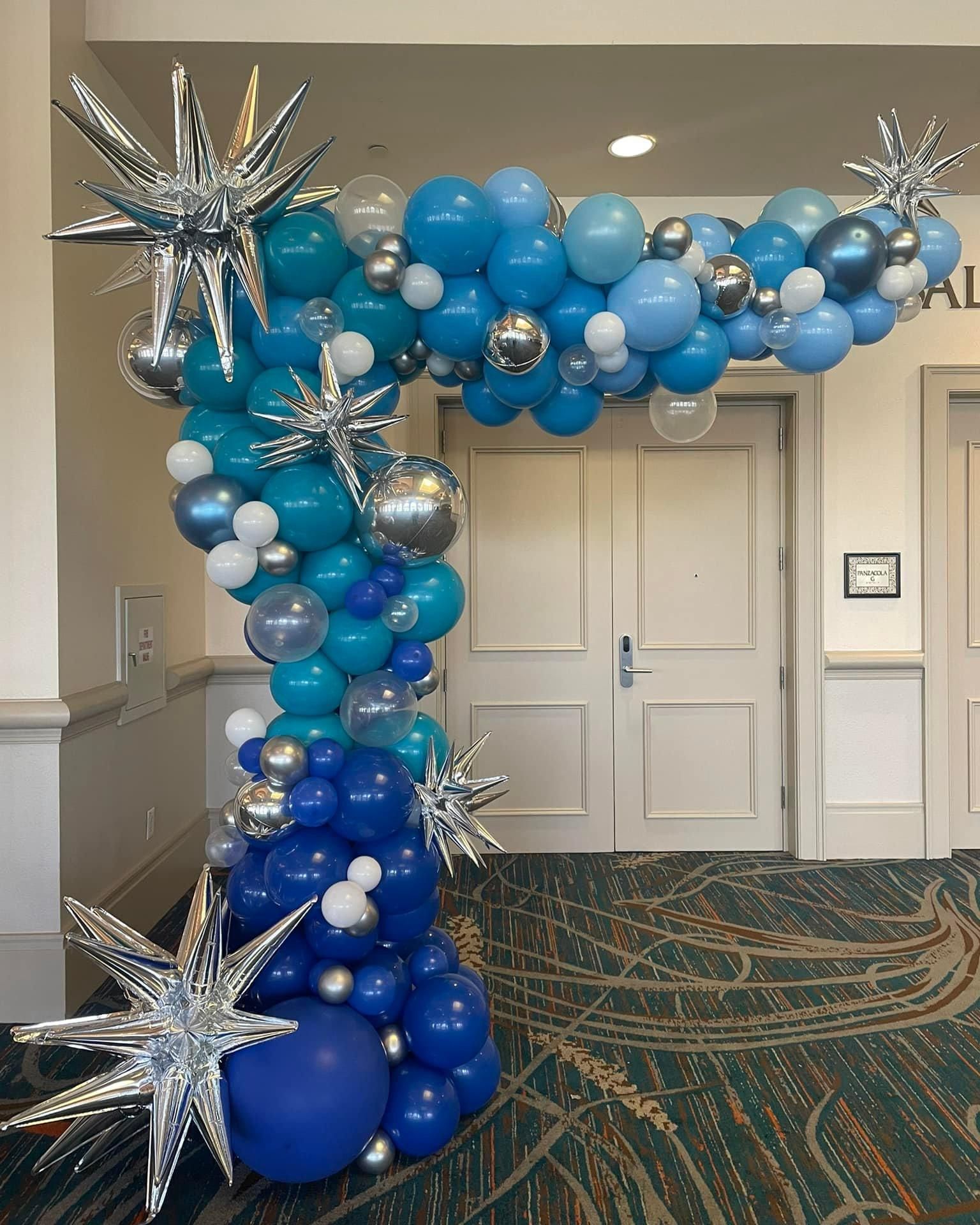A blue and silver balloon arch is in a hallway.