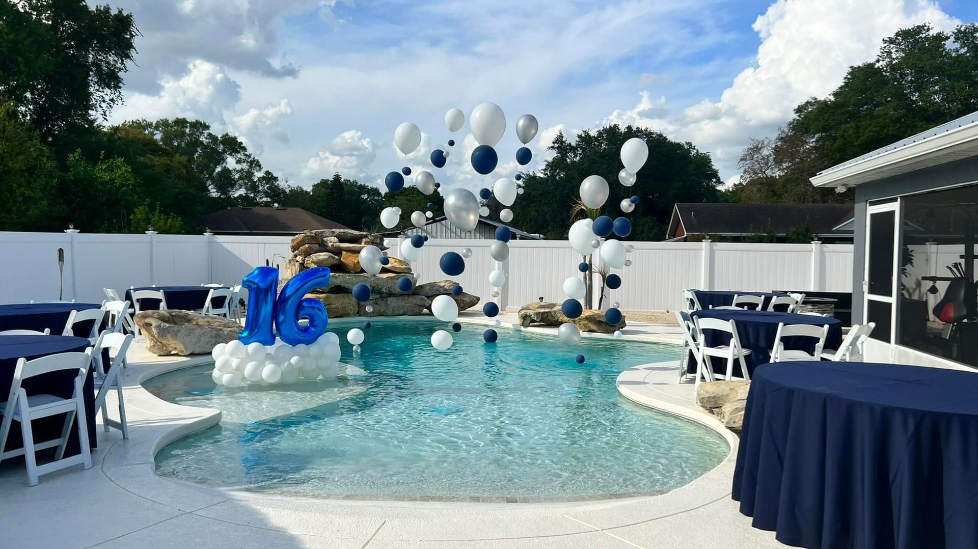 A swimming pool decorated with blue and white balloons and the number 16