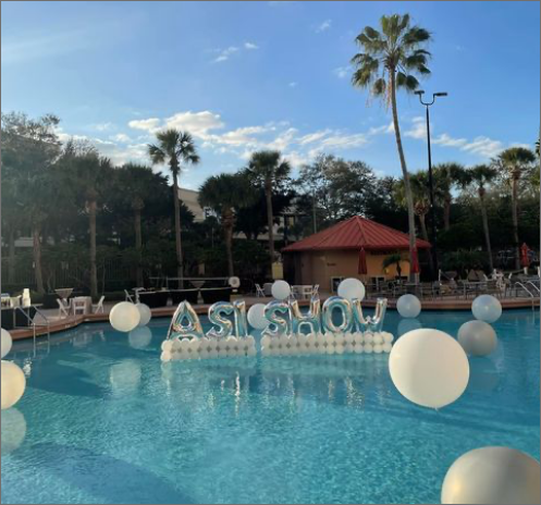 A swimming pool is decorated with balloons and a sign that says a si show
