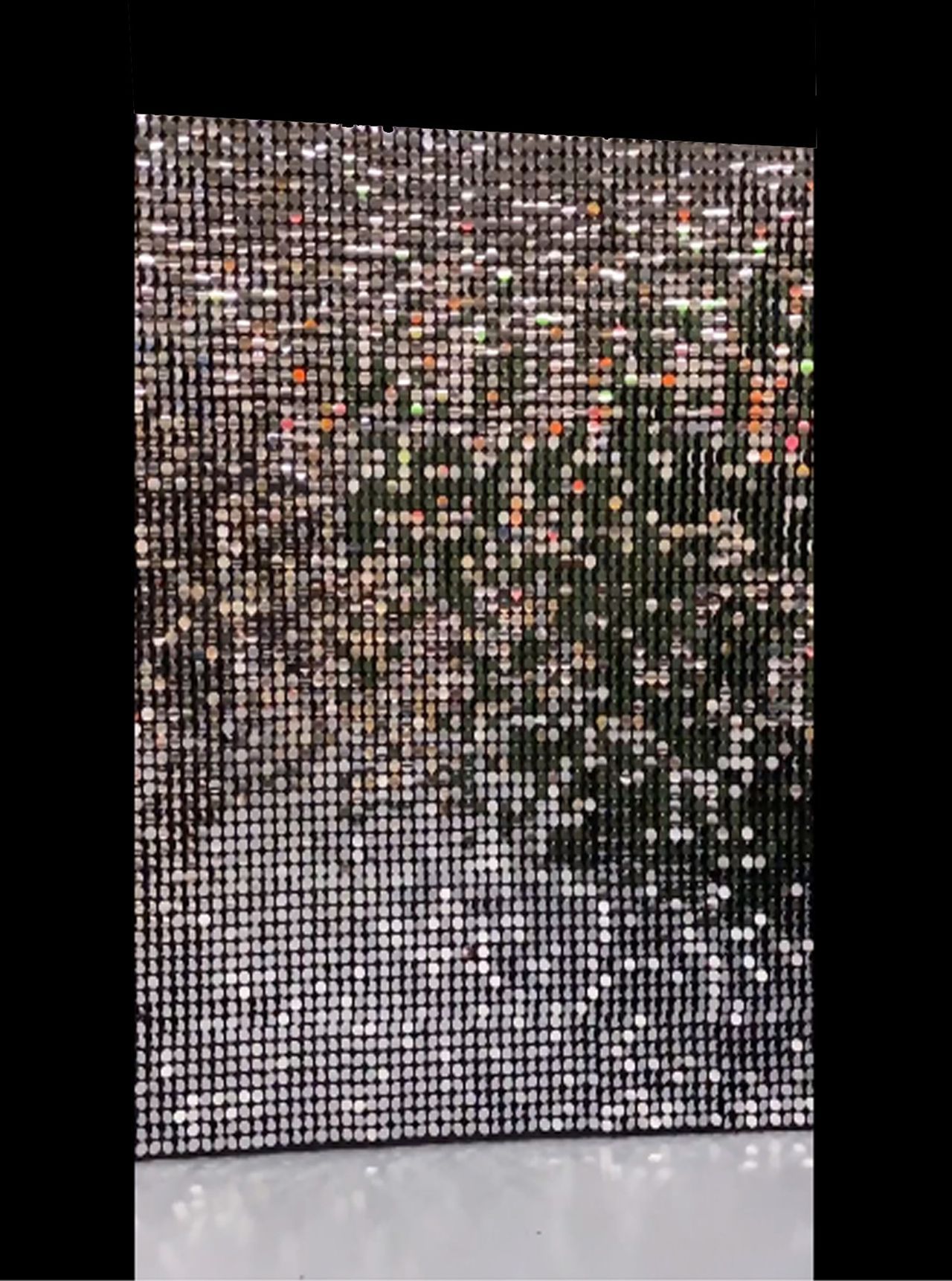 A picture of a wall made of sequins on a black background.