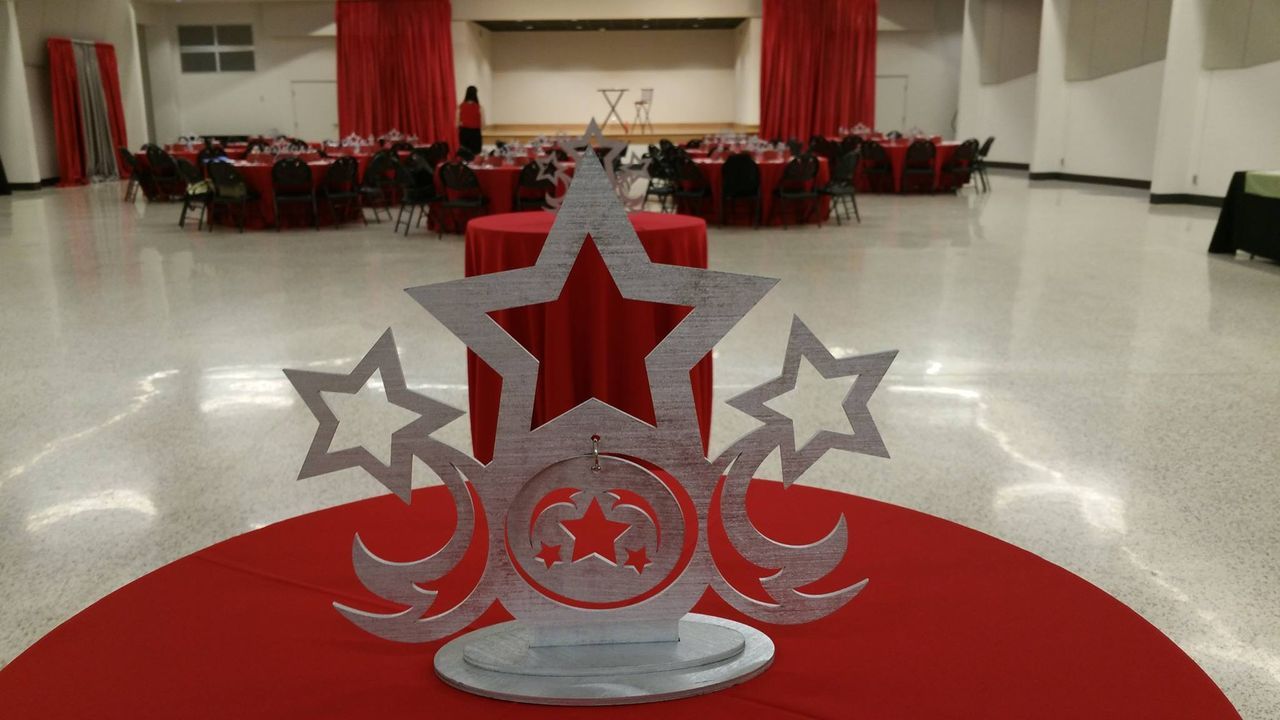 A silver star shaped decoration is sitting on a red table in an empty room.