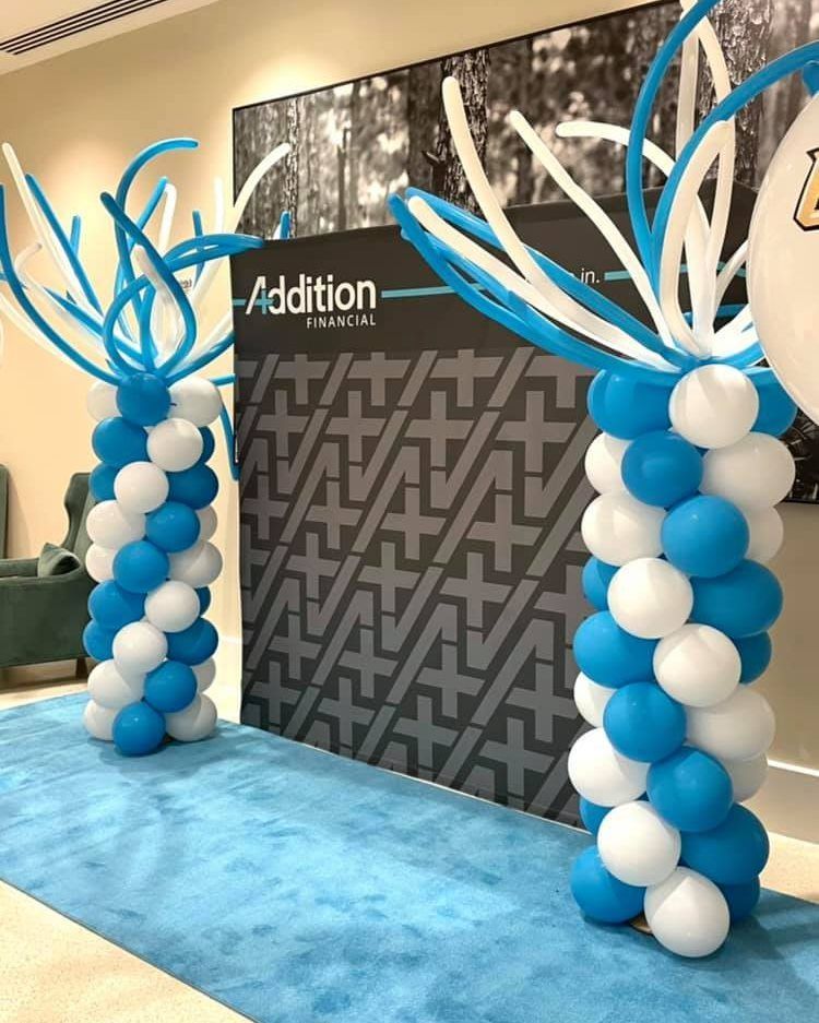 Blue and white balloons are lined up in front of a wall that says addition