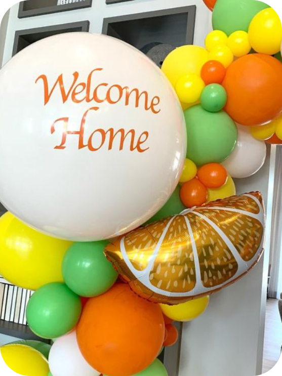 A bunch of balloons with one that says welcome home