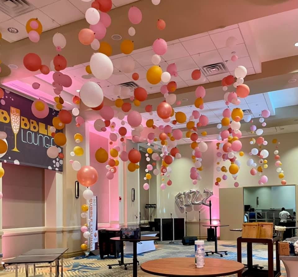 A room with balloons hanging from the ceiling and a sign that says bubble lounge