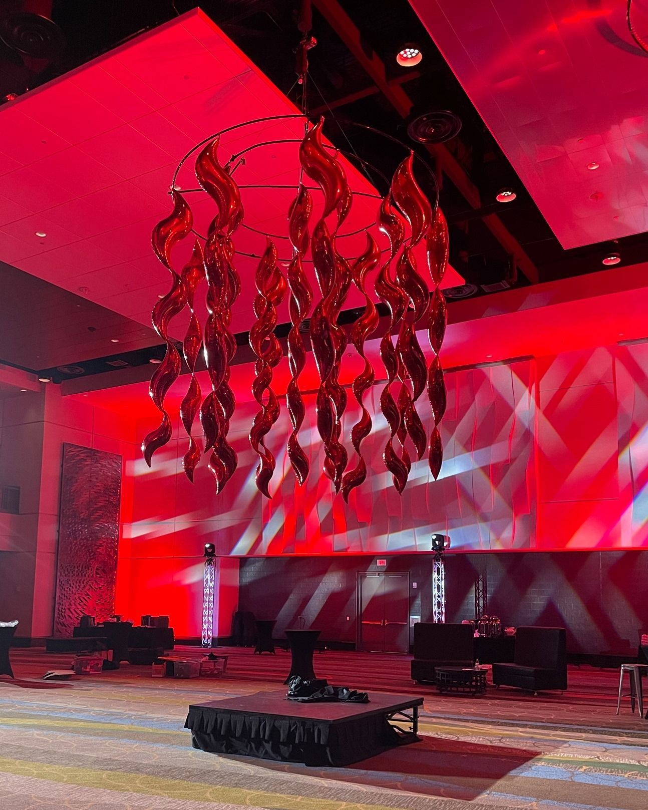 A large red chandelier is hanging from the ceiling of a large room.