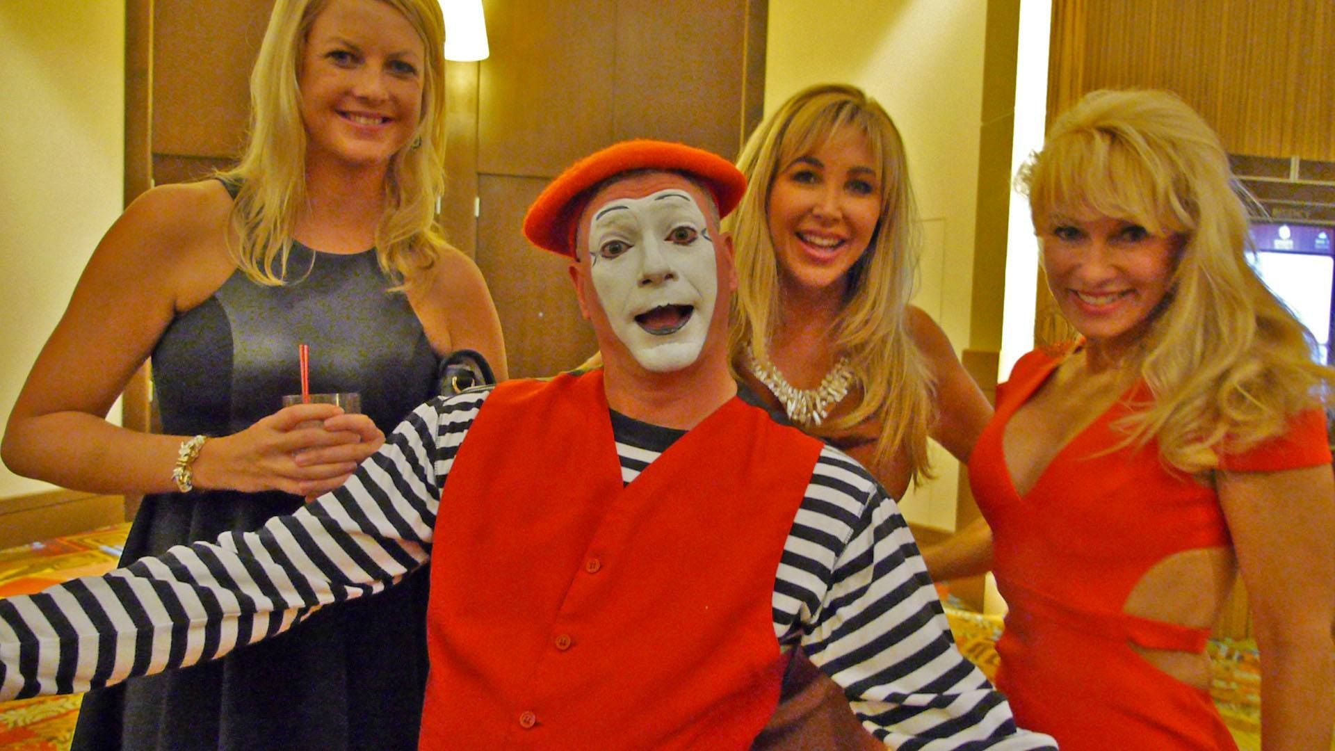A group of women are posing for a picture with a man dressed as a mime.