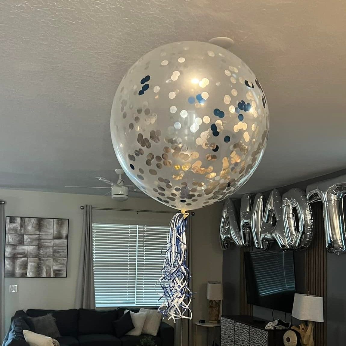 A large confetti balloon is hanging from the ceiling in a living room.