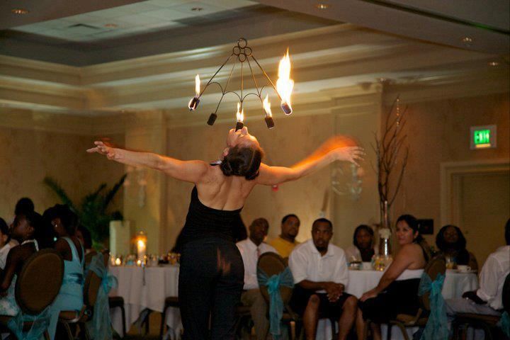 A woman is performing a fire show in a room with people sitting at tables.