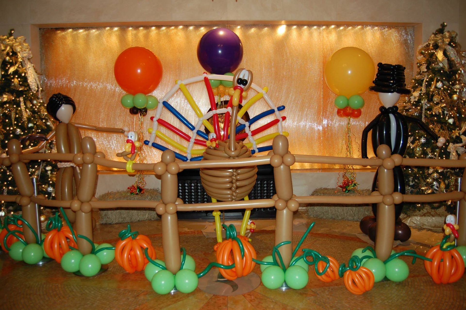 A turkey made out of balloons is surrounded by pumpkins