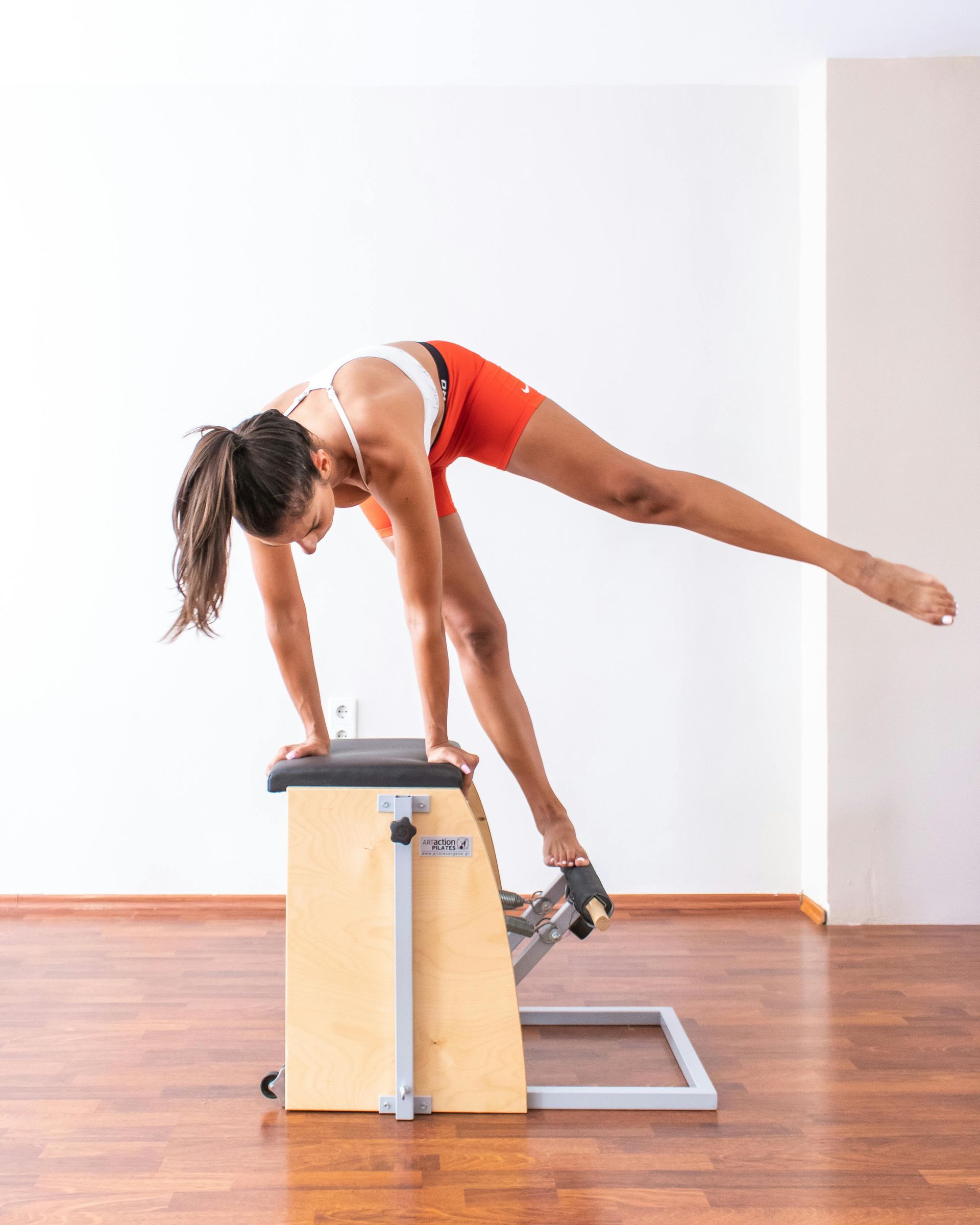 A woman is doing a yoga pose on a pilates machine.