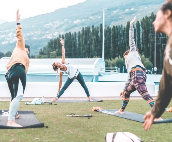 A group of people are doing yoga in a field with mountains in the background