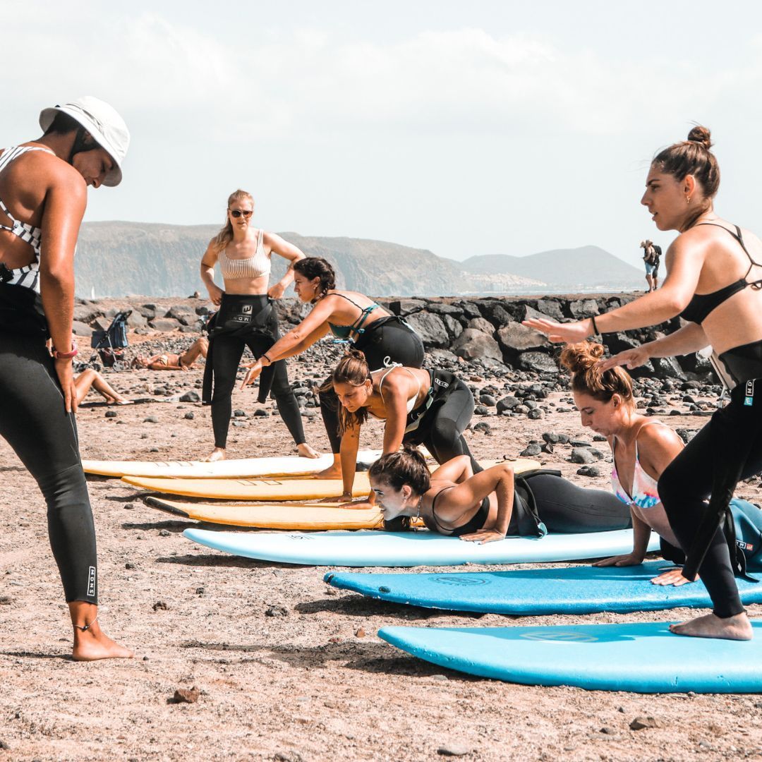 A group of women are standing on surfboards on a beach.