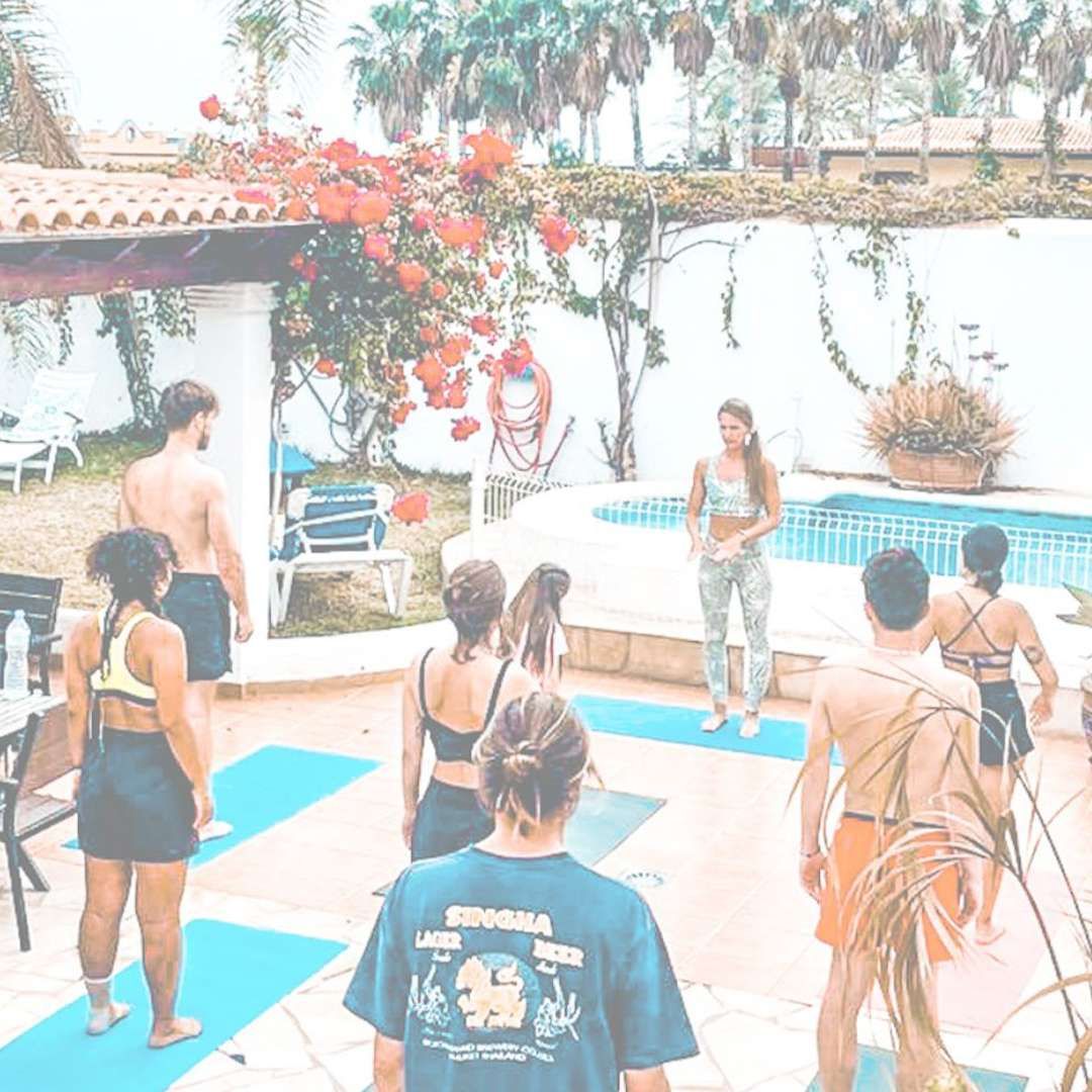 A group of people are standing on yoga mats in front of a swimming pool.