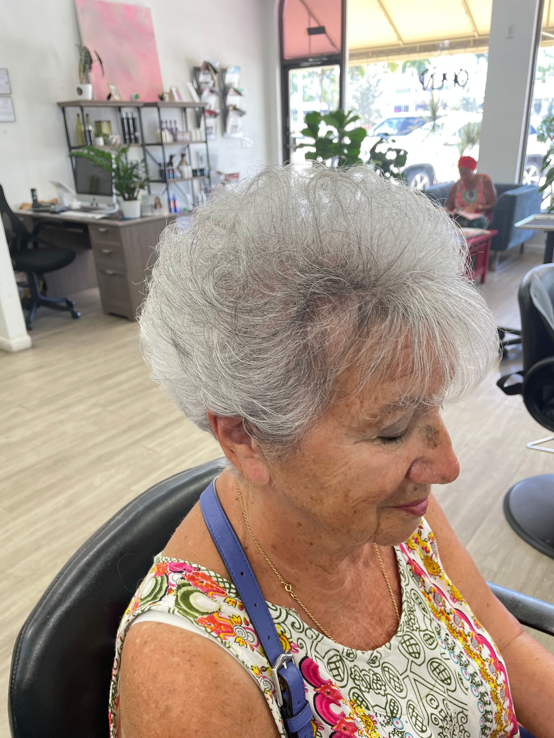 A woman with gray hair is sitting in a chair in a salon.