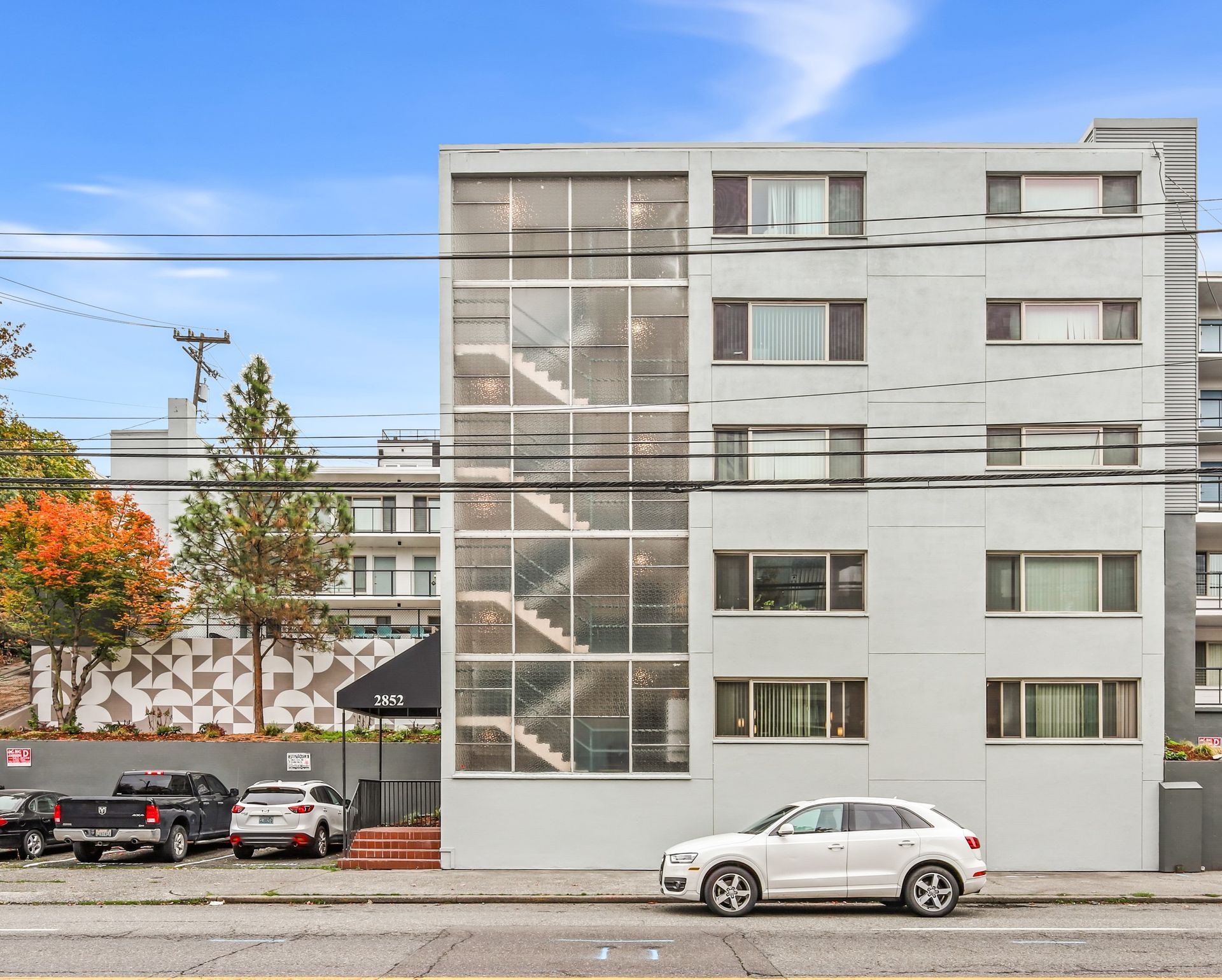 A white car is parked in front of a large building