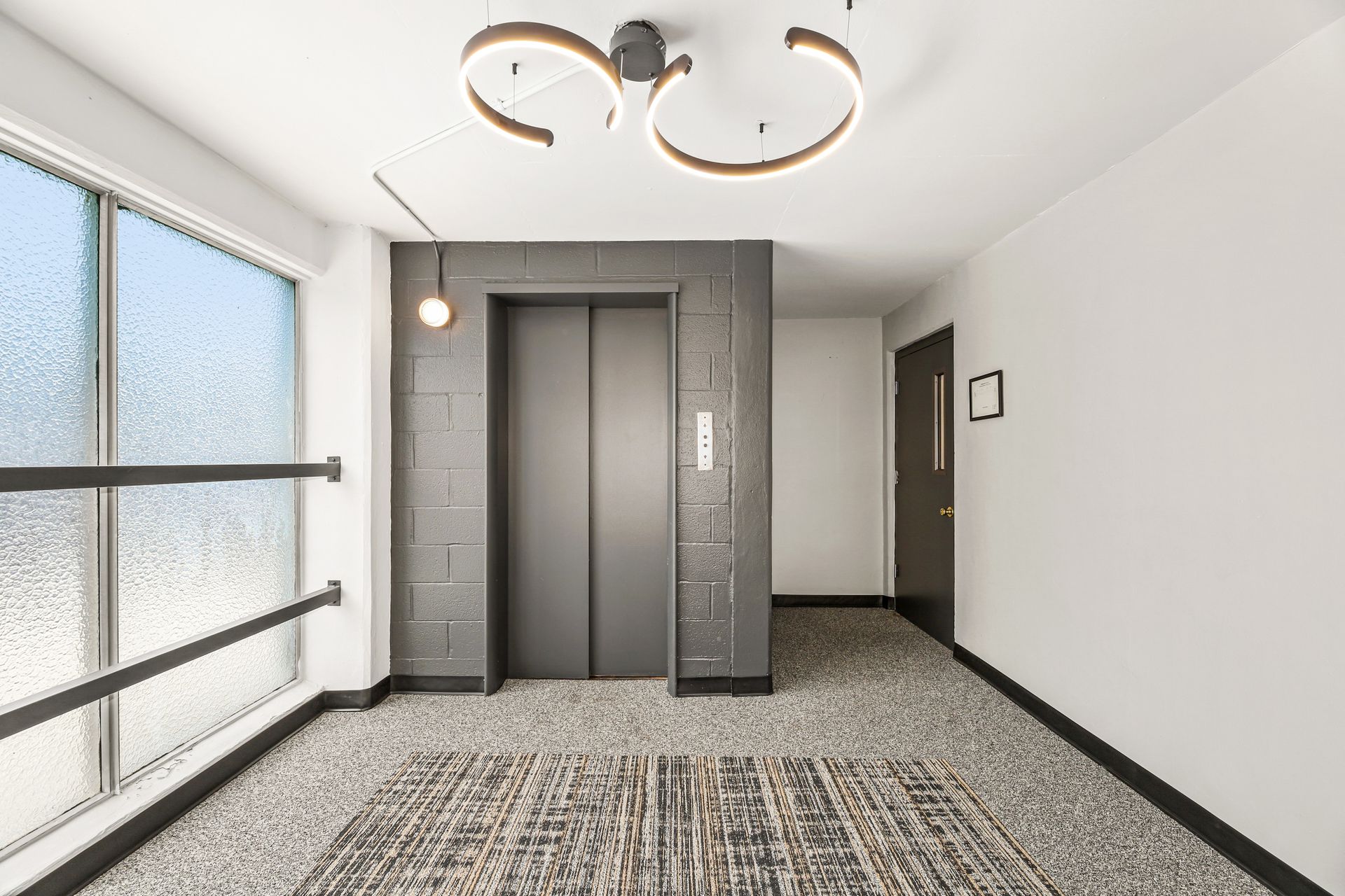 There is an elevator in the middle of the hallway.