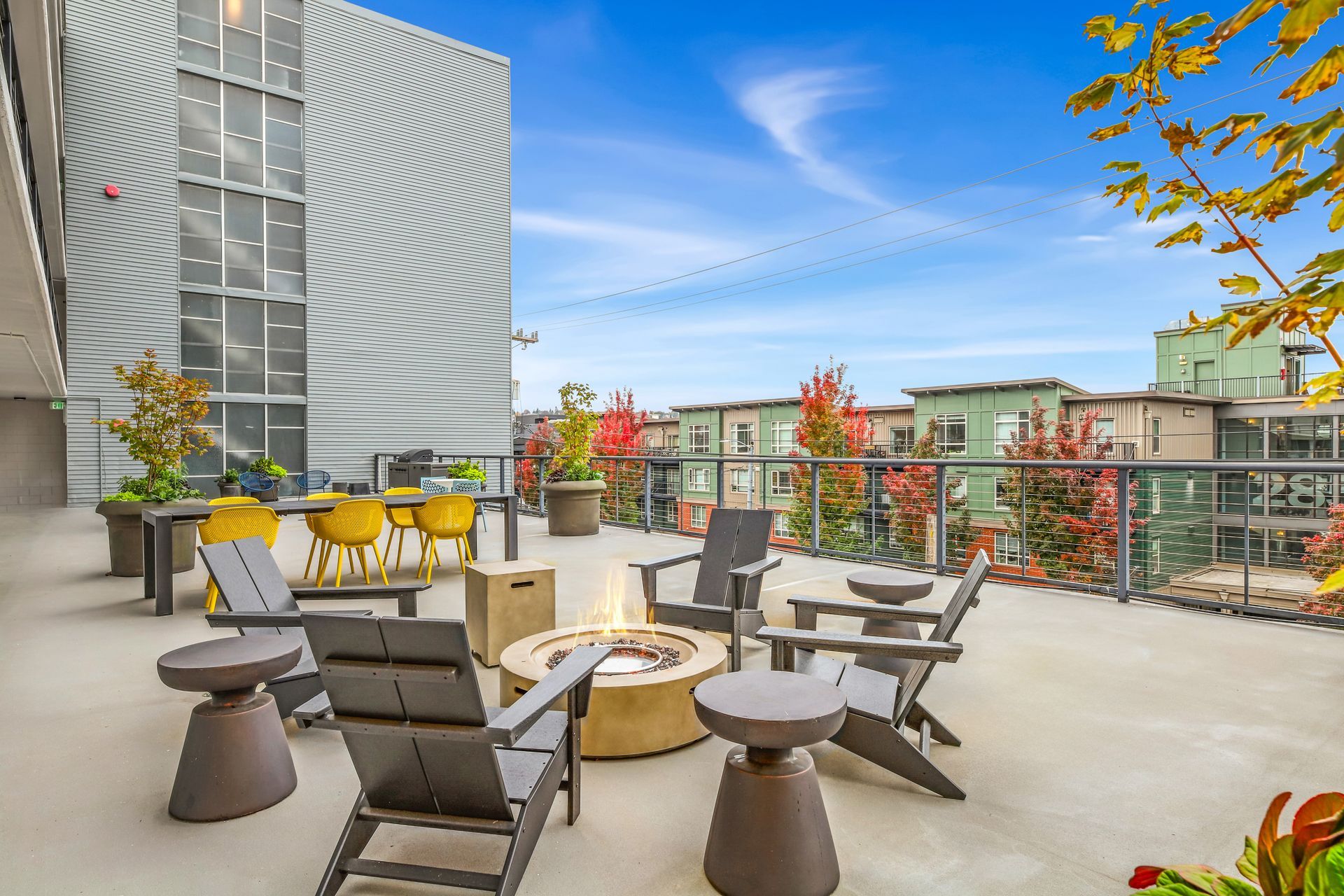 A patio with chairs and tables and a fire pit.