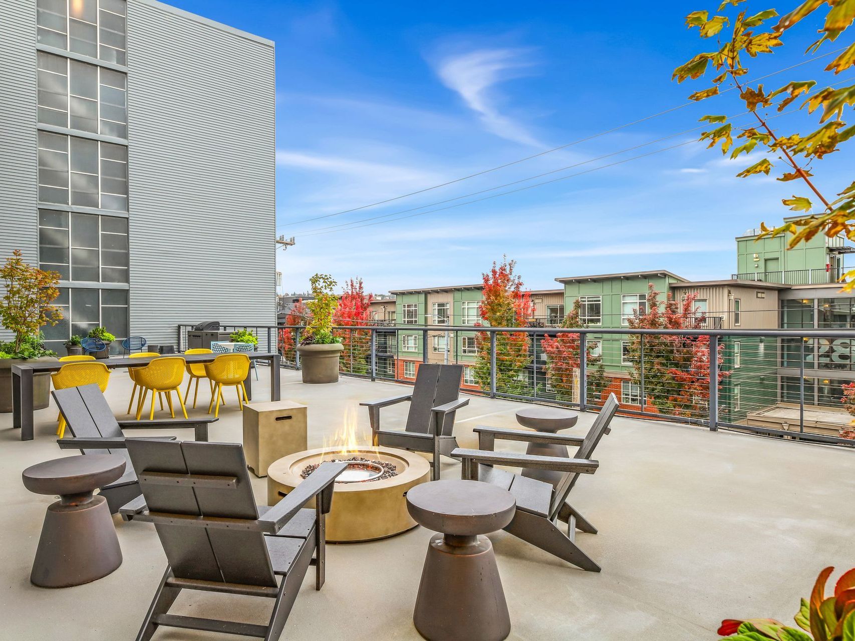 A fire pit is surrounded by chairs and tables on a patio.