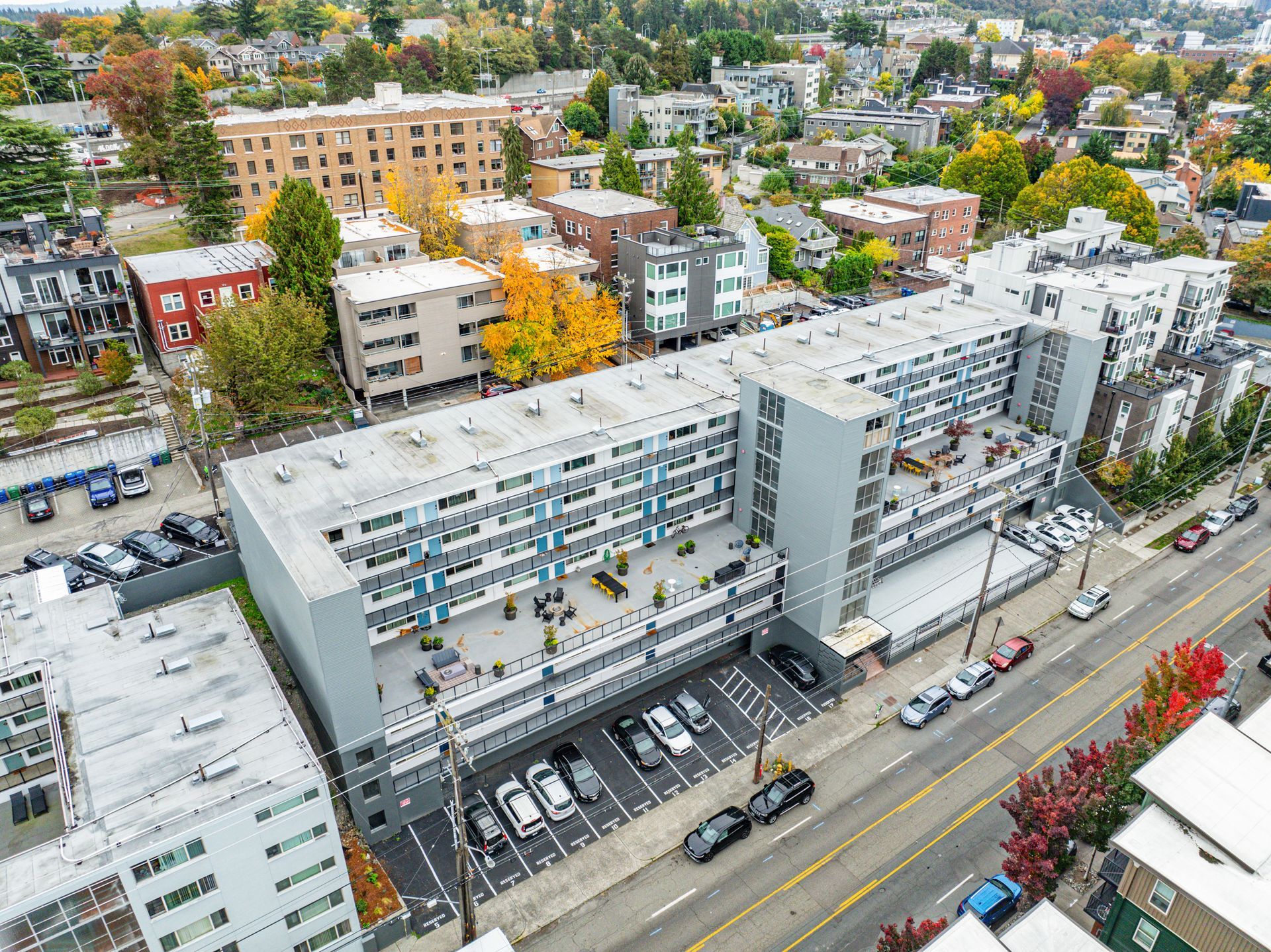 An aerial view of a large apartment building in a city with cars parked in front of it.