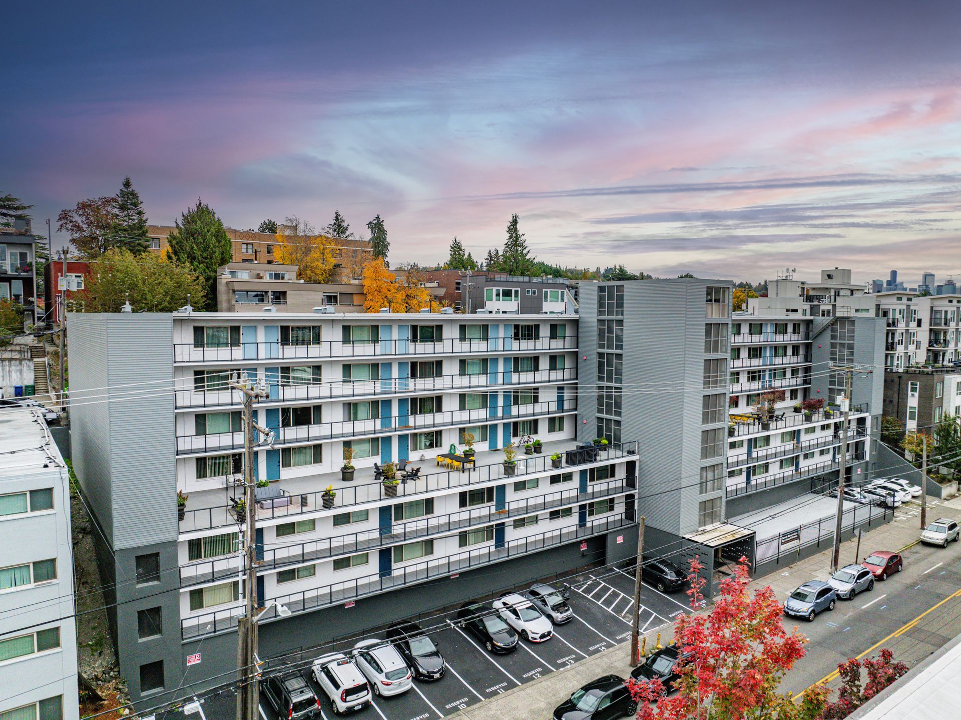 An aerial view of a large apartment building with cars parked in front of it.