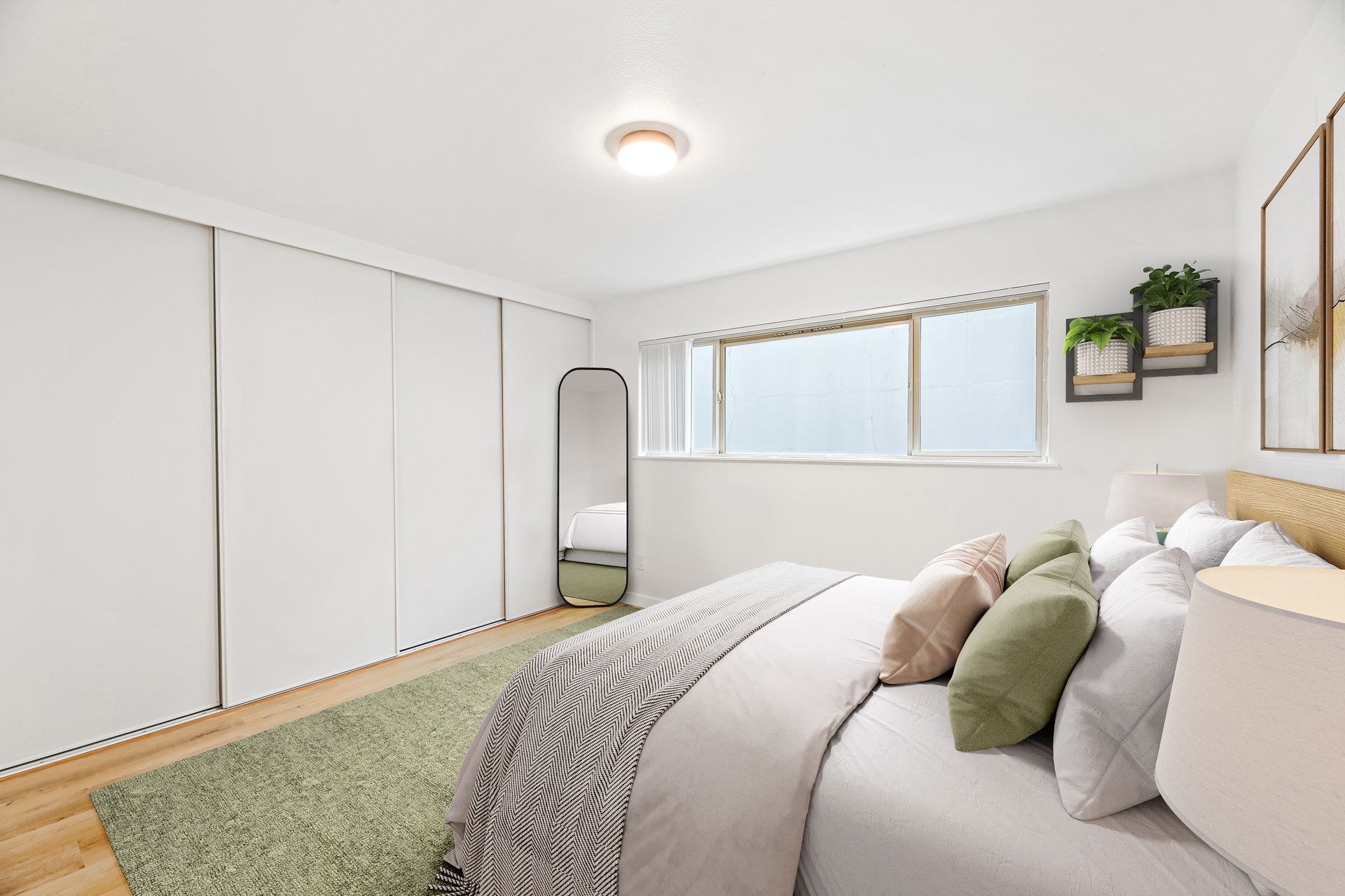 A bedroom with a large bed , a mirror and a window.