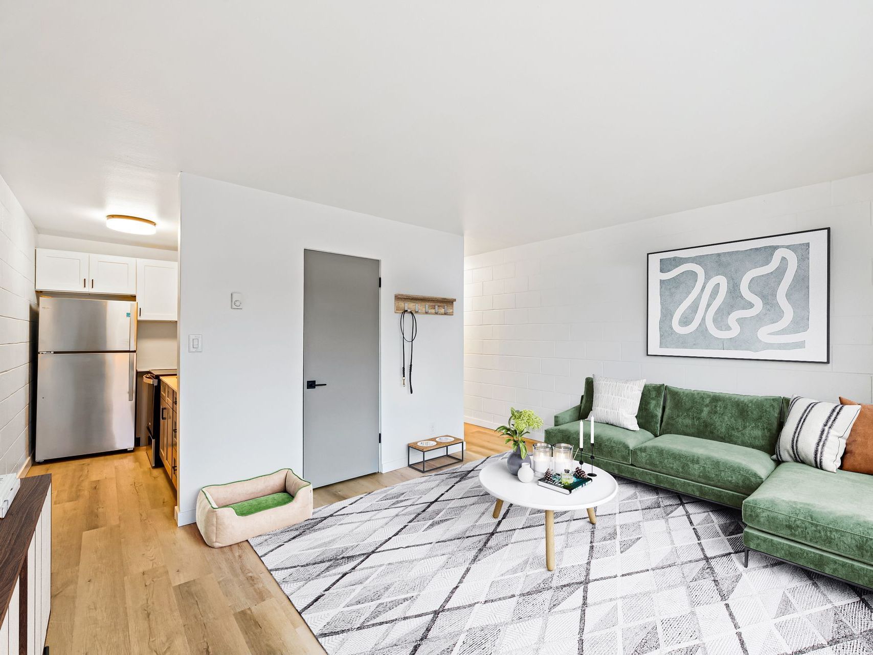A living room with a green couch and a white rug.