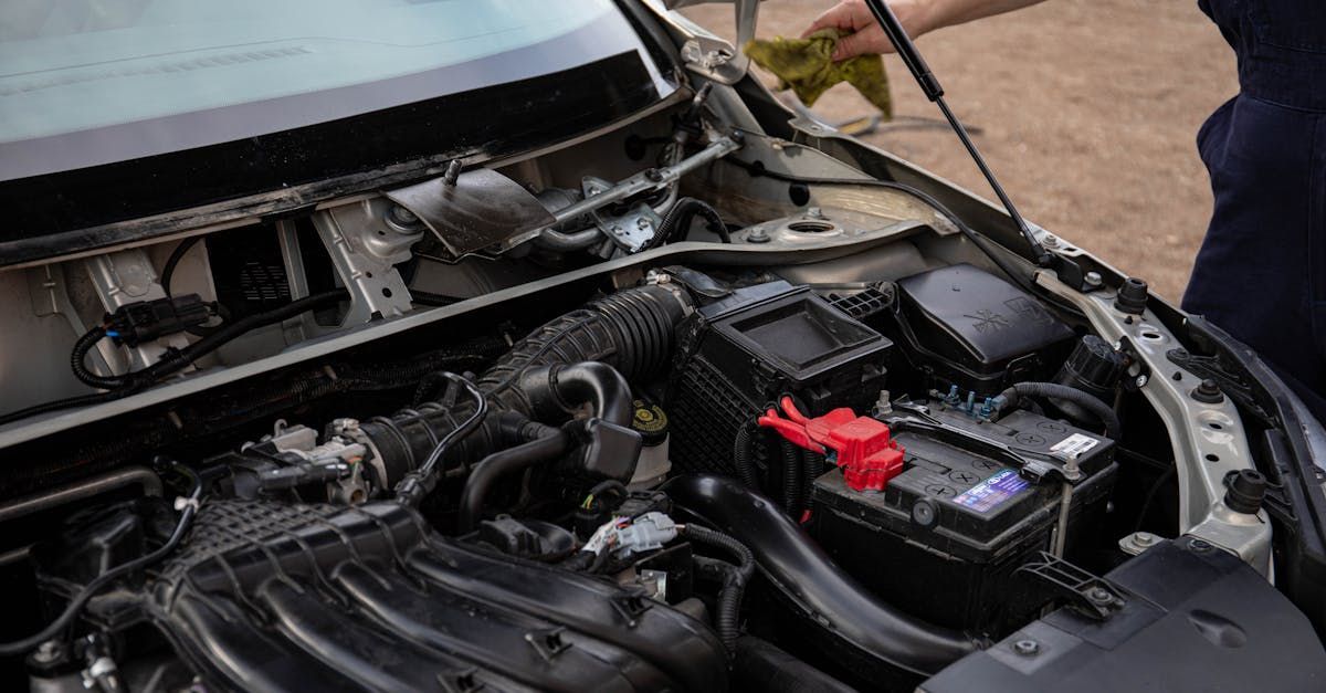 A person is cleaning the engine of a car with a cloth.  | Compton's Automotive