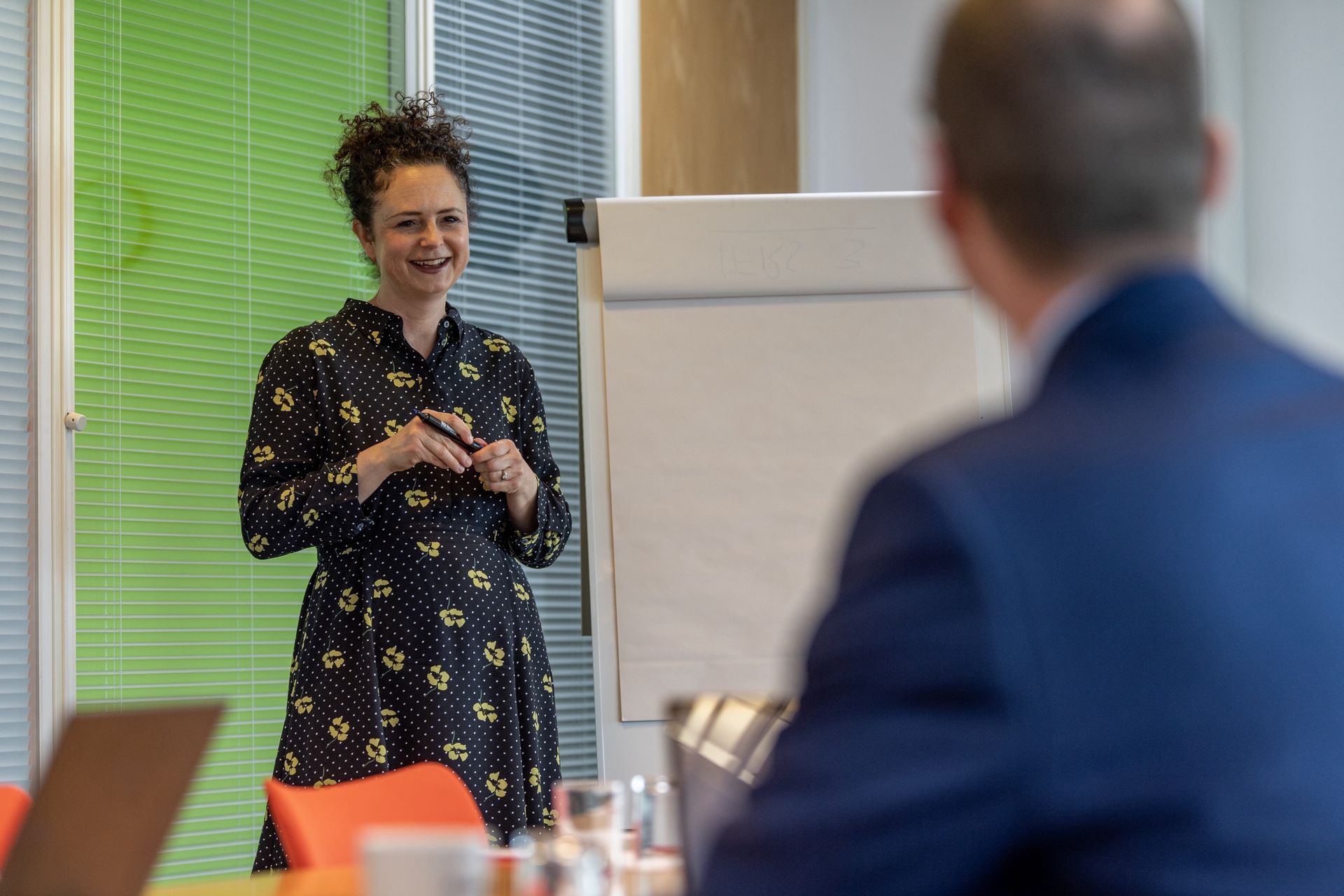 Kay is giving a presentation to a man in a conference room.